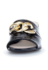 Chaussure noire en cuir verni à enfiler, avec bout ouvert et grande chaîne dorée brillante sur le dessus.