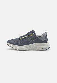 Sneaker in rete blu arioso con accenti gialli, suola VaporFoam bianca imbottita, punta arrotondata e suola sintetica per grip e supporto.