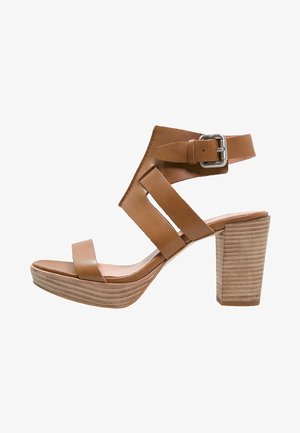 Sandal in pelle marrone con tacco alto, cinturino alla caviglia, punta aperta e tacco a blocco con strisce orizzontali per un effetto texture.