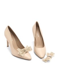 Beżowe szpilki z wydłużonym czubkiem. Dekoracyjna kokarda z jasnobeżowej siateczki z ozdobami z przodu. Gładka skórzana faktura.