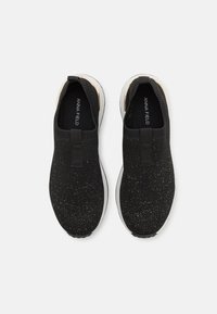 Paire de baskets noires en maille à enfiler avec semelles blanches et nom de la marque Anna Field visible à l’intérieur.
