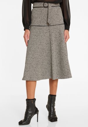Grauer und schwarzer Tweed-Midi-Rock mit hoher Taille, Gürtelschlaufen und A-Linie-Silhouette. Trägt schwarze Ankle Boots.