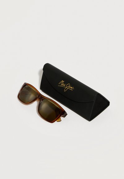Καφέ ορθογώνια γυαλιά ηλίου με σκούρους φακούς δίπλα σε μαύρη τριγωνική θήκη Maui Jim με χρυσό λογότυπο σε λευκό φόντο.