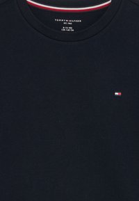 Mørkeblå bomulds t-shirt med rund hals; har et lille broderet logo i rød, hvid og blå på venstre brystområde.