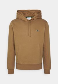 Brun hoodie med dragsko i huvan och känguruficka. Har en liten grön krokodil-logo på vänstra bröstet. Mjuk tygtextur.