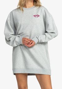 Vestido sudadera gris claro hecho de tela suave, con cuello redondo, mangas largas y un pequeño diseño de corazón rosa en el pecho.