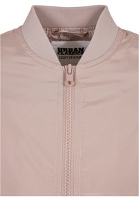 Light pink bomber jacket with ribbed collar and front zipper, size label visible inside neckline.