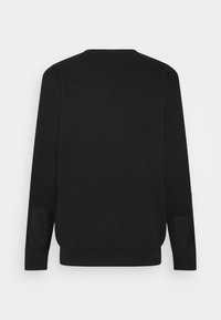 Sudadera negra con acabado texturizado, con mangas largas y escote redondeado. Los puños incluyen un detalle de panel en contraste.