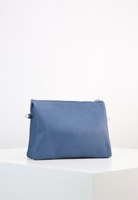 Modrá kožená kabelka s texturovaným povrchem, zipovým uzávěrem a decentním logem. Navržena v obdélníkovém tvaru se plochým dnem.