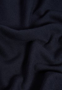 Tessuto lavorato a maglia di un blu navy scuro, di consistenza liscia e leggermente elastico. Presenta un motivo uniforme e un aspetto morbido e cadente.