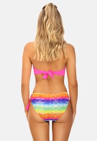 Zestaw bikini z jasnoróżowym topem na sznurki i spodniami w wielokolorowy gradient z falistą fakturą.