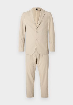 Completo beige a due pezzi realizzato in tessuto morbido. Giacca monopetto con due bottoni, abbinata a pantaloni con cordoncino. Design slim fit.