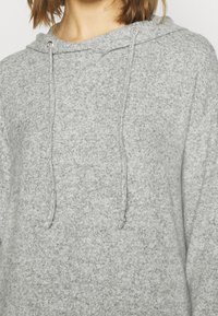 Hellgrauer Kapuzenpullover aus weichem, strukturiertem Stoff. Verfügt über eine Kordelzugkapuze und einen lockeren Schnitt für optimalen Komfort.