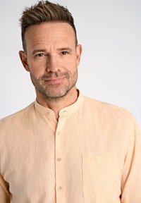 Camicia button-up pesco chiaro con colletto alla mandarina, taschino singolo sul petto e tessuto strutturato, accentuata da bottoni sobrii.