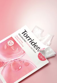 L'emballage du masque en gel Torriden présente un fond blanc avec une typographie noire en gras, des accents roses et une forme de masque en gel transparente visible.