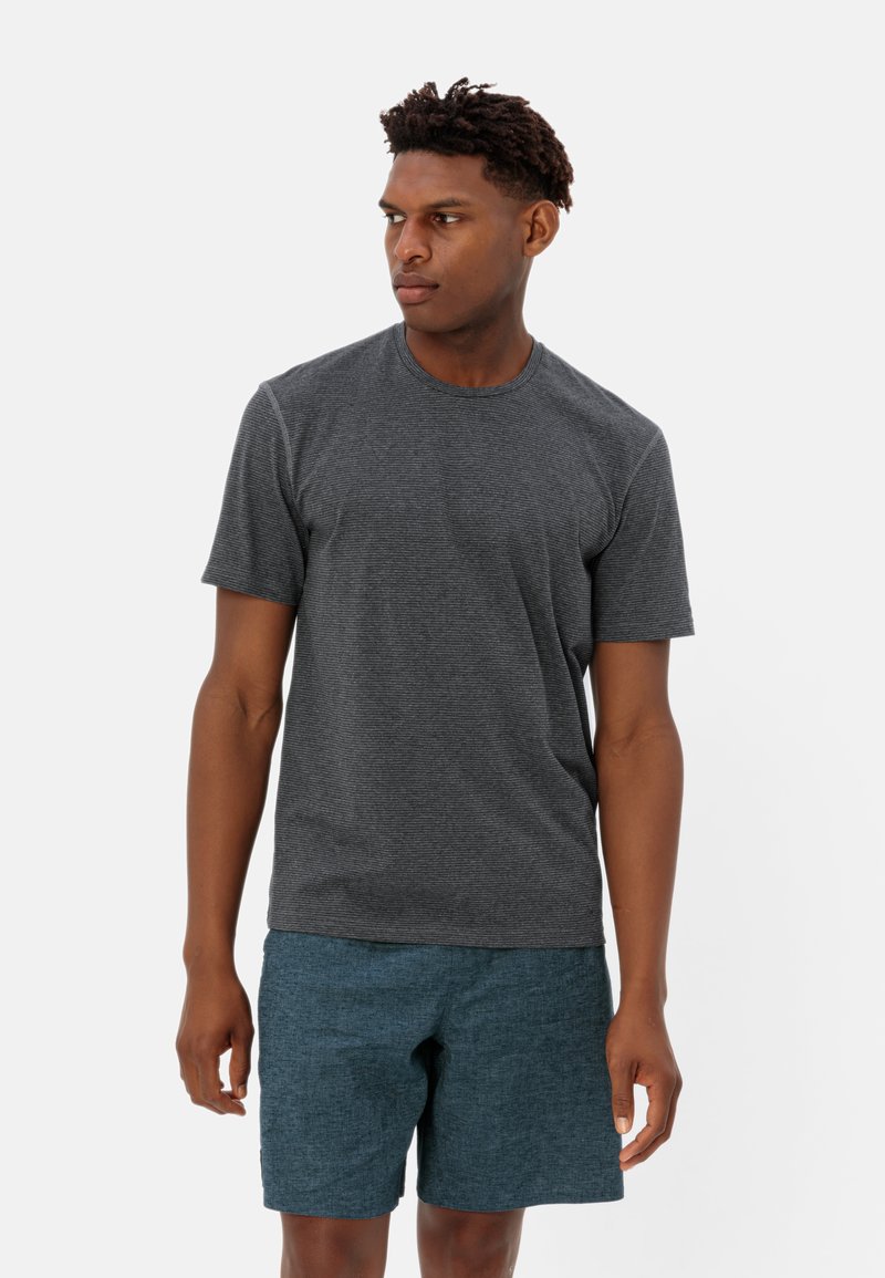 T-shirt noir gris à manches courtes avec un col rond, associé à un short texturé en teal, présenté sur un modèle se tenant devant un fond blanc.
