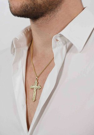 Goldener Kreuzanhänger-Halskette an einer dünnen Kette, mit filigranen Details, getragen über einem offenen weißen Hemd mit leicht ausgefranstem Kragen.