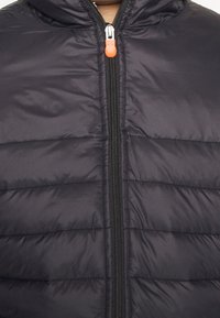 Giubbotto puffer blu navy con una texture liscia, cuciture orizzontali, zip frontale e un tirante arancione. Dotato di cappuccio per ulteriore calore.