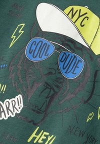 Grüner Stoff mit einem Tigermotiv, der blaue Sonnenbrillen, eine weiße Mütze mit der Aufschrift "NYC" und farbenfrohe Textelemente in verschiedenen Schriftarten zeigt.