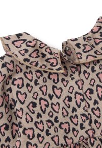 Strickkleid mit beigem Hintergrund, das ein Leopardenmuster in pinken und schwarzen Herzen zeigt. Mit einem Kragen und Druckknöpfen ausgestattet.