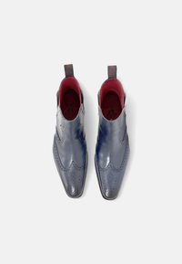 Botas de tobillo de cuero en azul marino con detalles de medallón tipo brogue, interior rojo, lengüetas en la parte superior y un acabado suave y pulido.