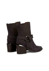 Botas de tobillo de ante morado oscuro con acentos de tachuelas, detalle de hebilla y tacón apilado. Textura suave con un diseño de punta afilada.