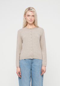 Light beige cardigan with a round neckline, long sleeves, and a button front. Soft texture, fitted cut, paired with loose blue jeans.