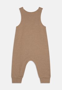 Tan ribbesert jumpsuit med brede skulderstropper, rund halsutskjæring og elastiske mansjetter; har en avslappet passform og lavt skritt-design.