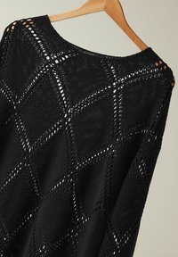Schwarzer Strickpullover mit offenen Rautenmuster, strukturierten Stichen und weitem Ausschnitt, präsentiert an einem Holzkleiderbügel.