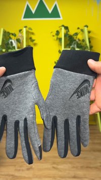 Gray knit gloves with black textured palms and cuffs. Features a raised black logo on each wrist. Suitable for various activities.