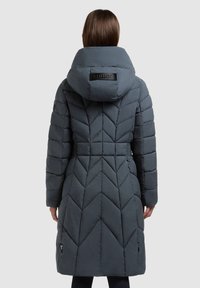 Siva puhasta jakna z vzorcem cik-cak prešitega perja, visokim ovratnikom in blagovno znamko na hrbtni strani. Izdelana iz mehkega, trpežnega materiala.