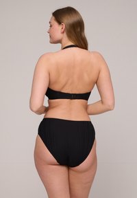 Czarny bikini z prążkowanej tekstury. Top na szyję i wysokie majtki z zapięciem z tyłu. Prosty design.