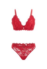 Soutien-gorge en dentelle rouge avec bretelles réglables et motif floral ; string en dentelle assorti avec bords festonnés et étiquette. Les deux présentent une texture transparente.
