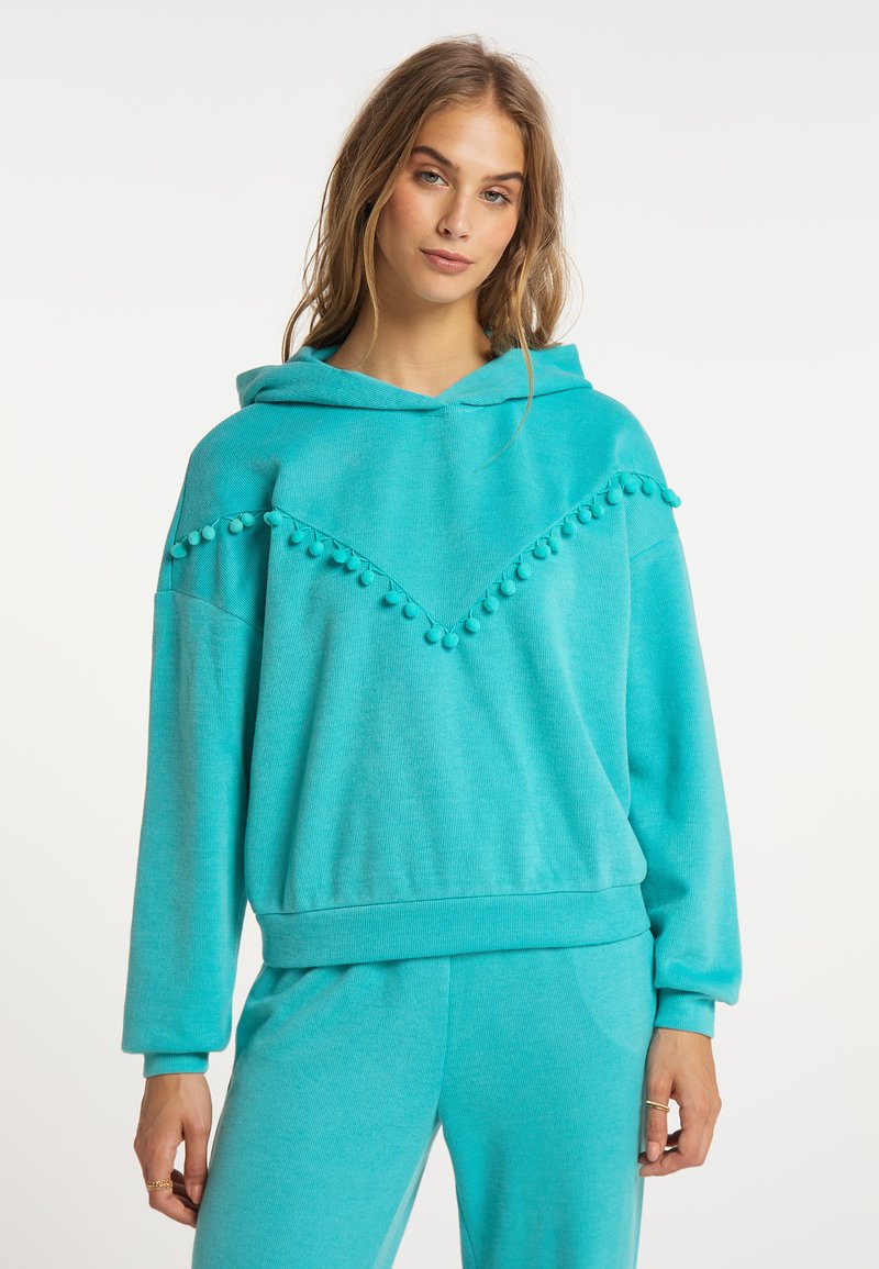 Felpa con cappuccio turchese in tessuto morbido. Presenta un design a chevron con dettagli a pom-pom lungo il collo e una vestibilità comoda.