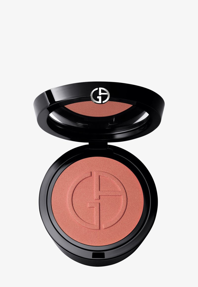 Poudrier à blush avec un couvercle noir brillant. Présente une poudre ton pêche avec un léger éclat, un design de logo en relief et une forme ronde.