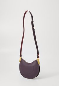 Purple leather shoulder bag with a curved shape, gold hardware accents, and an adjustable strap. Textured surface with a zip closure.