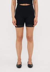 Sorte stretchshorts med en tettsittende design, med en blonderkant ved kanten. Utsmykket med en myk tekstur og elastisk midje.