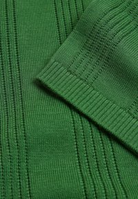 Grüner Strickstoff mit gerippten und strukturierten Mustern, Nahaufnahme mit gefaltetem Bündchenrand.