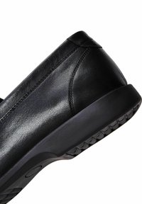Zwarte leren schoen met een gladde textuur, ronde neus en rubberen zool met een gegroefde zool voor grip. Minimalistisch ontwerp.