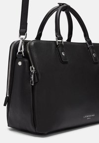 Sac à main en cuir noir avec doubles poignées, bandoulière détachable, fermeture éclair argentée et logo embossé à l'avant. Texture lisse, forme structurée.