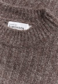 Hnědý pletený svetr s texturovaným vzorem, s vysokým límcem a štítkem označeným "KAREN BY SIMONSEN" na výstřihu.