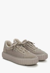 Beige suède sneakers met een zachte voering, ronde neus, tonale veters en een dikke, gegroefde rubberen zool. Branding op de zijkant.