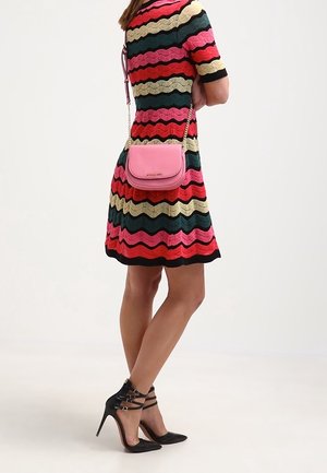 Lyserød crossbody-taske med en glat tekstur, rektangulær form og kæderem, kombineret med en kjole med flerfarvet zigzag-mønster.