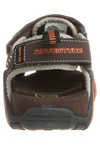 Brązowe i beżowe sandały przygodowe z odkrytymi palcami, z pomarańczowymi akcentami i regulowanym paskiem opatrzonym napisem "ADVENTURE" widziane z tyłu.