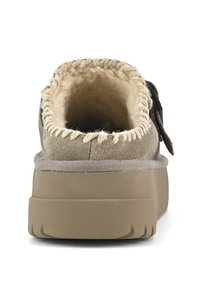 Chaussure en daim marron avec une finition texturée, forme arrondie, doublure intérieure douce et semelle plate-forme avec un motif en vagues.