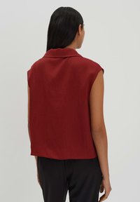 Blusa bordeaux con colletto e maniche corte; tessuto leggero e testurizzato; design fluido con orlo dritto. Vista posteriore.