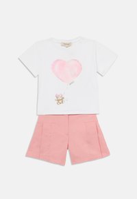 T-shirt bianca a maniche corte con un grafico di un palloncino a forma di cuore rosa e un orsetto, abbinata a pantaloni corti plissettati rosa chiaro.