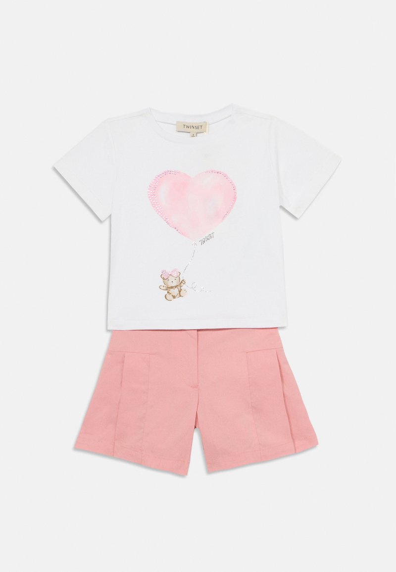 T-shirt bianca a maniche corte con un grafico di un palloncino a forma di cuore rosa e un orsetto, abbinata a pantaloni corti plissettati rosa chiaro.