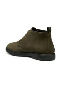 Botas de tobillo de ante marrón con punta redonda, dos ojales y suela de goma negra. Incluyen una pestaña en la parte posterior para facilitarlas.