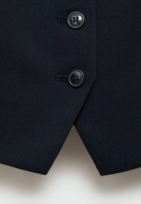 Marineblaues Stoffweste mit einem scharfen Ausschnitt, ausgestattet mit zwei runden schwarzen Knöpfen und einer glatten Textur. Die Nähte sind in der Nähe der Knöpfe sichtbar.